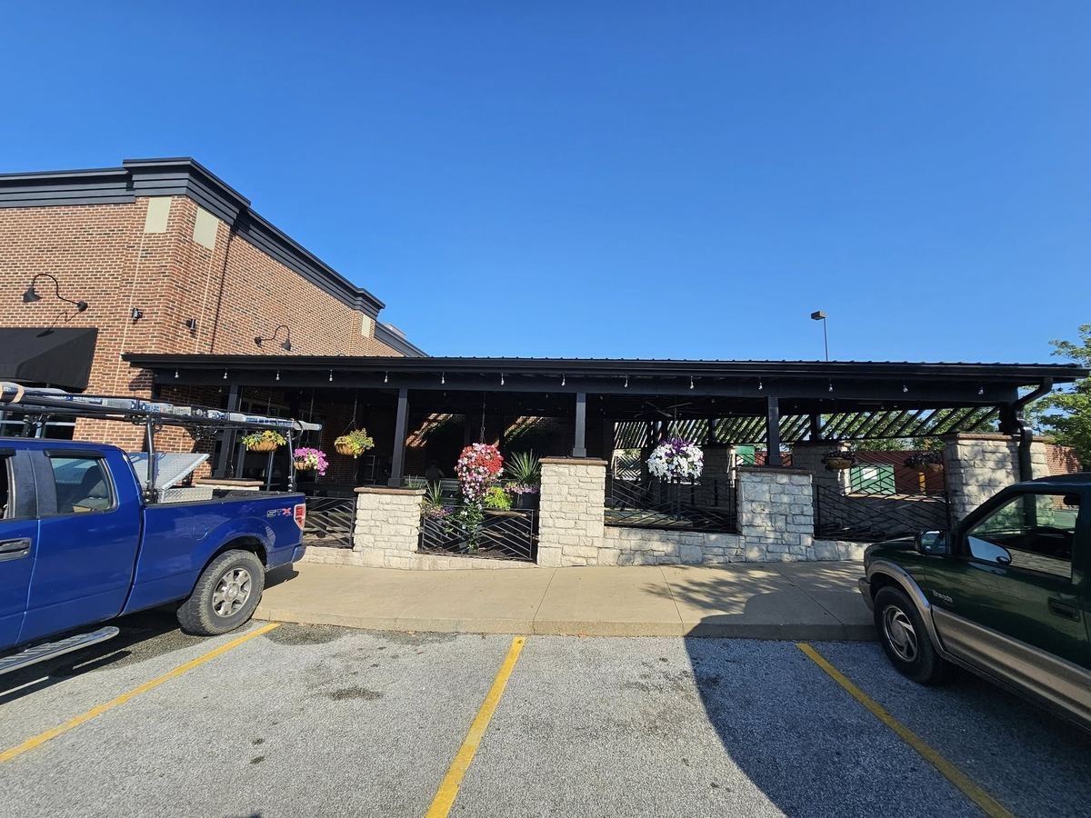 Commercial building with a dark metal roof over its covered patio, with a Crawford work truck parked in front.