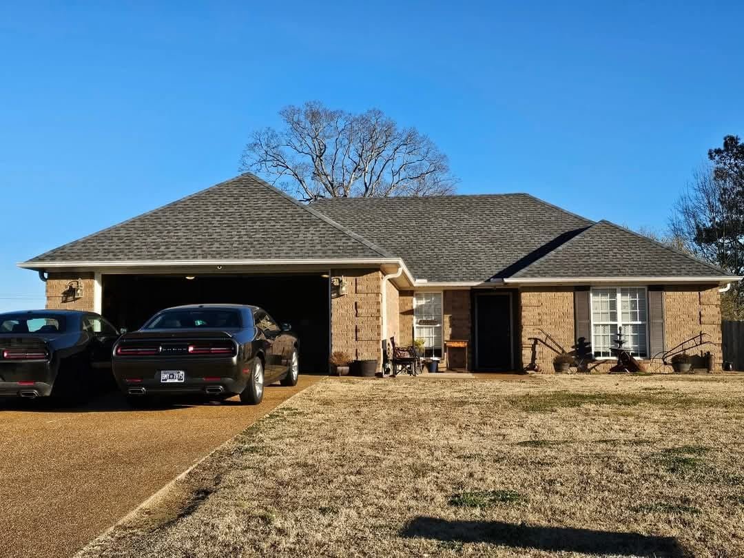 Brick ranch home with a new charcoal architectural shingle roof and a two-car garage, under a clear winter sky.